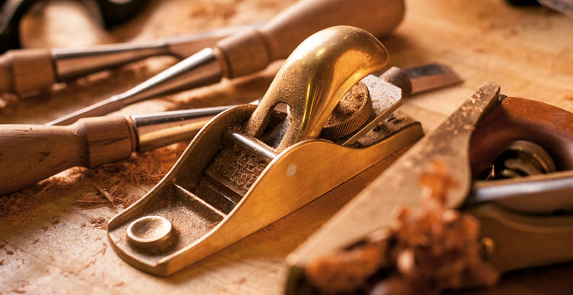 A brass Lie-Nielsen block plane resting on a workbench among chisels and
wood shavings